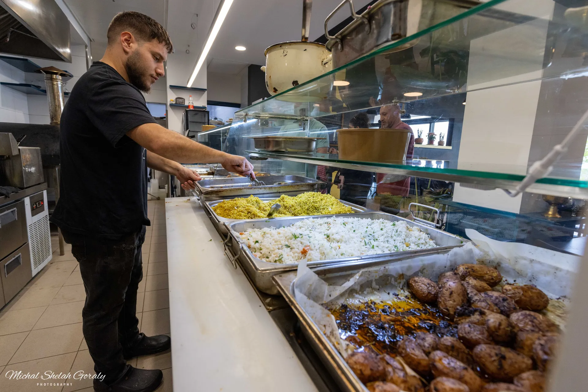 השף רוסלן ליד דלפק המנות החמות במסעדה