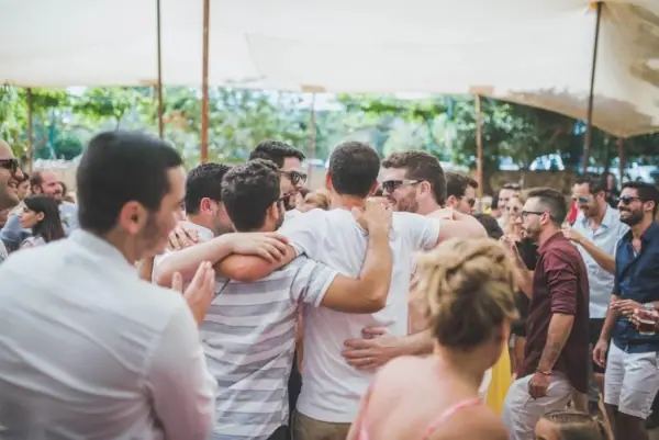 קבוצת חברים מתחבקת ורוקדת מתחת לסככה