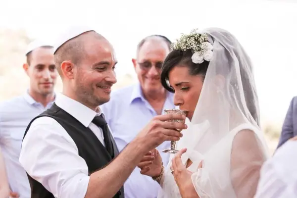 חתן וכלה טועמים יין בטקס, בסביבת המשפחה