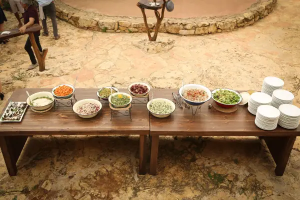 מזנון סלטים ותוספות על שולחן עץ בחצר